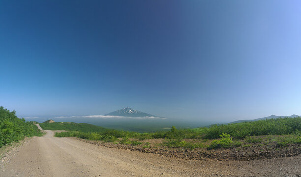 Iturup island landscape with Bogdan Hmelnicky volcano summit above the layer of low clouds