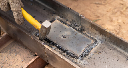 Skilled worker hammers hot metal weld in industrial workshop, capturing the artistry of...
