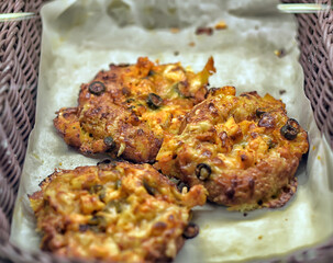 Fresh, ruddy mini-pizzas with olives, cheese and vegetables in a basket on parchment paper.  