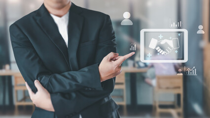 A businessman in a suit points to a virtual interface with a handshake icon, symbolizing a business partnership, deal agreement, and successful collaboration.