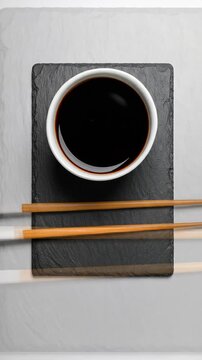 Soy Sauce in White Bowl with Chopsticks on Black Slate Offers an Authentic Asian Cuisine Still Life Presentation