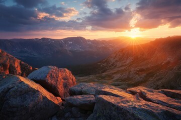 Majestic mountain landscape at sunrise with golden light illuminating rocky foreground and dramatic clouds