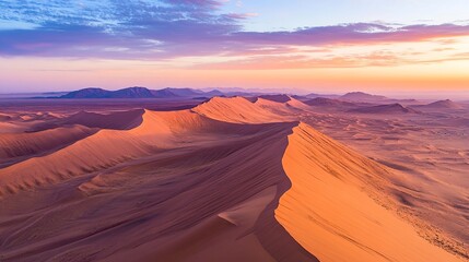 Naklejka premium Wide aerial shot of an endless desert, golden sand dunes creating intricate patterns, with shadows stretching across the vast, barren landscape