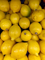 Close-up view of a vibrant pile of fresh yellow lemons with glossy skin, stacked together at a local market.