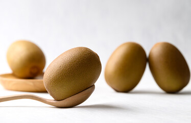 Fresh kiwi fruit with wooden spoon and plate on white background, Healthy eating