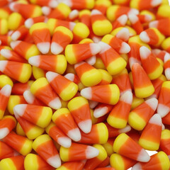 A closeup, overhead view of a large pile of colorful candy corn, a popular sweet treat often enjoyed during the autumn and halloween season