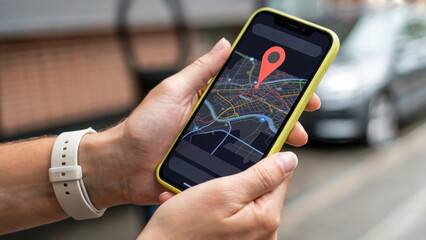 Hands holding smartphone with navigation app showing city map and location pin, outdoor setting