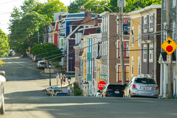 Obraz premium Colorful houses line Duckworth Street while people chat at the corner of Victoria Street, capturing the friendly vibe of downtown St. John's.