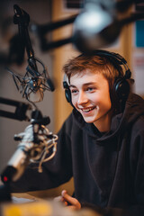 Early evening in a small radio studio with headphones and microphones A young host is talking about youth leadership on a community show