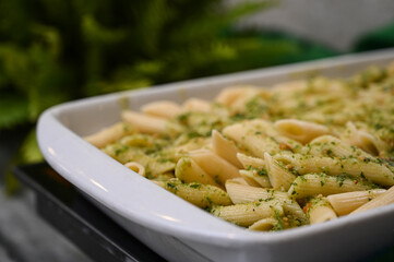 penne pasta, penne pasta with pesto sauce in white dish, italian pasta with basil pesto close-up, delicious green herb pasta served fresh, penne with pesto sauce
