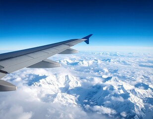 Airplane wing view above snowy mountain range and clouds under a vibrant blue sky