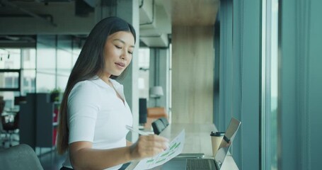 The Modern Businesswoman is diligently analyzing complex data in a contemporary office space - Powered by Adobe