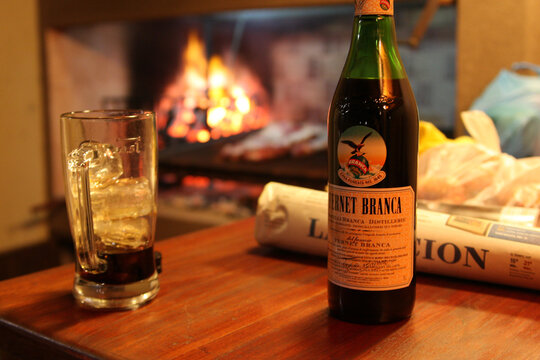 Bottle of Fernet Branca with Glass and Asado in Background
