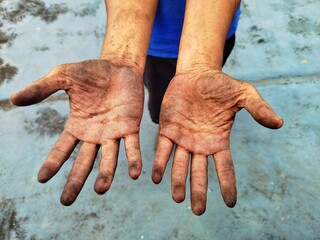 Dirty hands of a worker, stained with soil and grime after a day of labor. Close-up shot, showing...