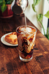 Cream Swirling into Iced Coffee with Pastry