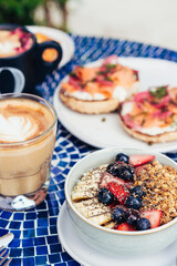 Breakfast Bowl with Granola, Bananas, and Berries Beside Latte