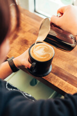 Barista Finishing Latte Art in Black Ceramic Cup