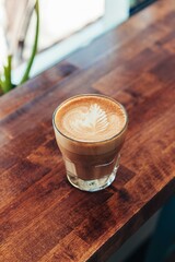 Glass of Latte with Leaf Latte Art on Wooden Counter