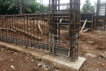 The reinforced concrete structure under construction has clearly connected steel bars for columns and beams set on a lean concrete base.