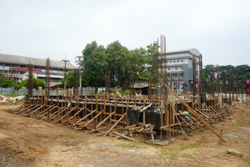 Construction of foundations and ground beams using rebar cages encased in concrete formwork with timber bracing used to support and secure the concrete formwork in preparation for pouring concrete.