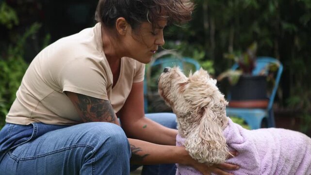 Woman drying her wet cockapoo dog with a purple towel