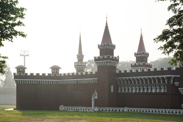 Red brick castle with turrets and battlements on a misty morning. Fairytale-like fortress architecture creating a majestic and historic landmark scene.