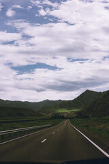 Remote asphalt road runs through the wild steppe of Altai, Russia, heading directly to a snowy ridgeline. A perfect image of isolation and raw natural beauty.