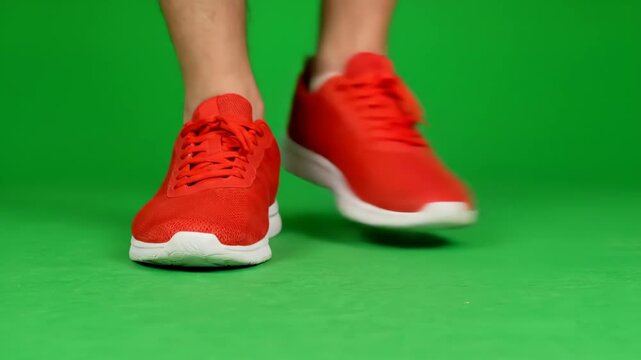 Red Sneakers Tap Dancing on Green Screen - Close-up shot of a person's feet in red athletic shoes performing a tap dance shuffle against a vibrant green screen background.