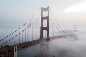 A suspension bridge covered in morning mist