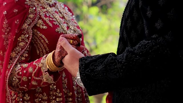 Groom is holding brides hands in Traditional henna painting. Red color is the traditional Indian clothes, Elements of hindu wedding. 