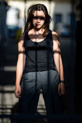 Teenager posing on urban street. Stylish teen girl with confident look. Urban youth lifestyle captured naturally. Shadow portrait of teen girl. Confident young woman posing outside.