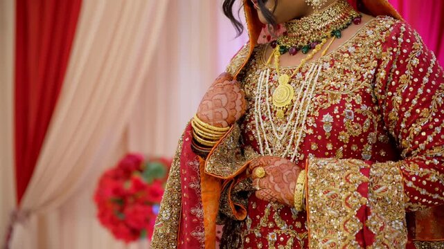 Bride is keeping her hands in traditional manner posing for photo, dressed in red traditional Indian clothes, Elements of hindu wedding. 