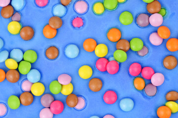 Blue icing with scattered sugar shell covered chocolate beans cake decoration background texture