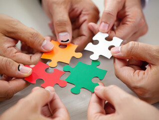 Closeup of hands connecting colorful puzzle pieces, symbolizing teamwork, collaboration, and problemsolving