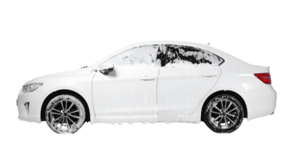 A white car covered in foam, highlighting its sleek design and shiny wheels.