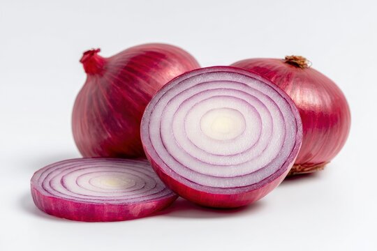 Three red onions on a white background two whole and one sliced in half with a slice in front
