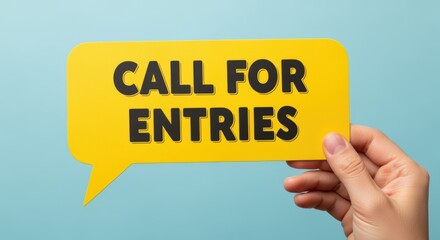 Hand Holding Yellow Speech Bubble with Call for Entries Message on Blue Background