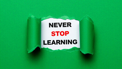 Green paper torn revealing text never stop learning message