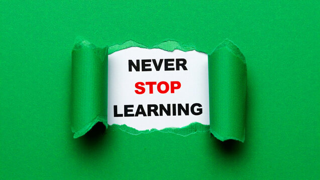 Green paper torn revealing text never stop learning message