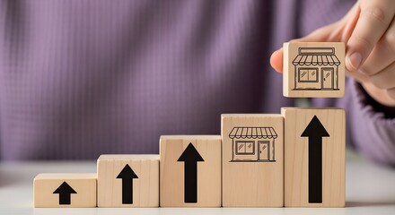 Hand stacking wooden blocks with shop icons forming an upward growth staircase symbolizing business expansion and success