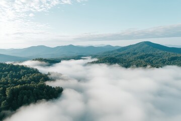 Obraz premium Panoramic Mountain Vista: A breathtaking panoramic shot, where verdant mountain range peaks emerge gracefully through a sea of ethereal clouds, with a bright blue sky above.