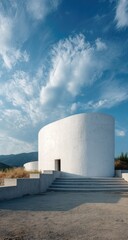 White, rounded chapel, steps leading up,  against a vibrant blue sky with fluffy white clouds