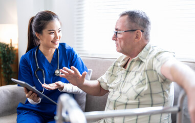 Fototapeta premium Smiling nurse in blue scrubs talking with elderly man using a walker, providing healthcare advice and support at home.