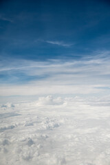 Aerial view of fluffy white clouds under a blue sky with wispy clouds