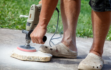A man is using a power tool to sand a piece of wood