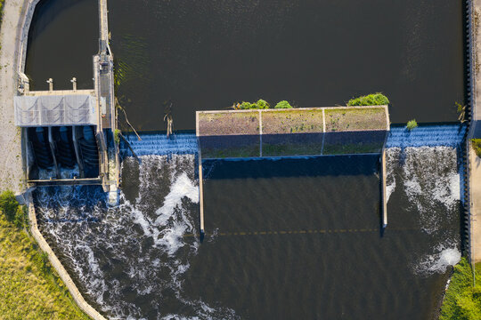 Top-down aerial view of Woolston Weir on the River Mersey in Warrington, a hydroelectric facility harnessing the river&rsquo;s flow, with water cascading over the structure