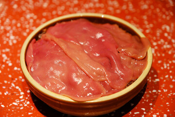 close up of a bowl of sliced raw pork kidney
