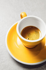 Close-up View of Rich Espresso Shot in Yellow Cup on Light Gray Table
