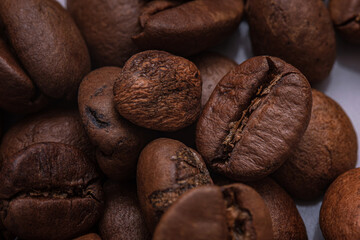 Roasted coffee beans close-up. Macro shot of roasted coffee beans highlighting their rich brown tones, textured surfaces and natural oils.