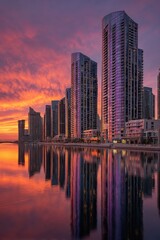 Fototapeta premium Modern cityscape at sunset, reflected in calm water